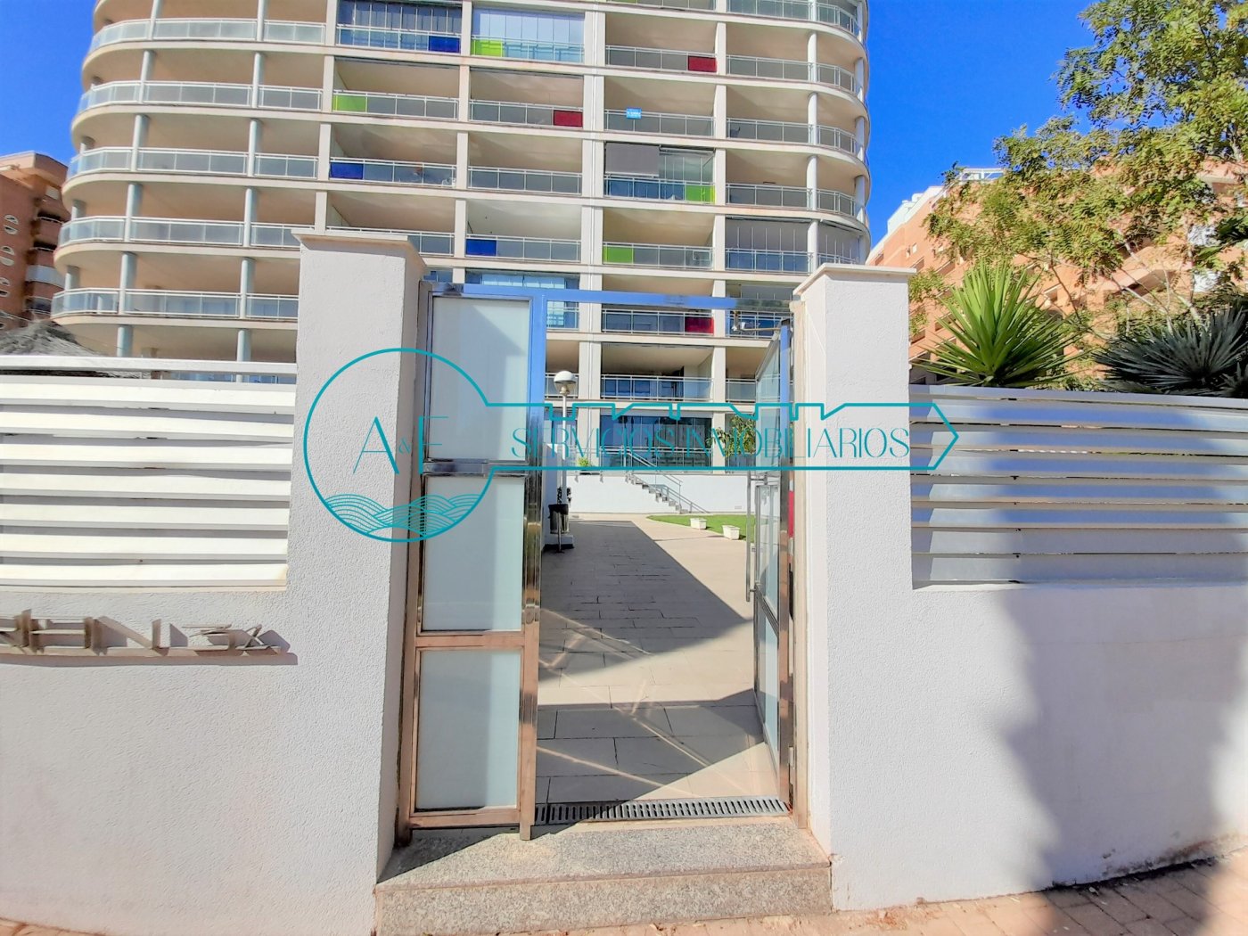 Ejemplo de un apartamento en Oropesa del Mar con vistas al mar con zona comunitaria. Fotografía del bloque de apartamentos visto desde la entrada a la urbanización. A yF Inmobiliaria Oropesa del Mar reserva tu piso de alquiler de vacaciones en la playa